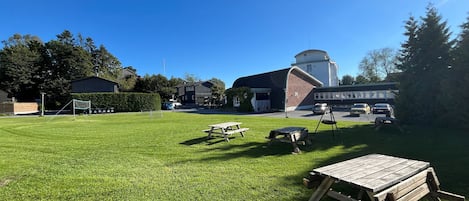 A grassy outdoor area with picnic tables and a swing set.