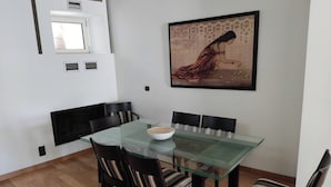 A dining area with a glass-top table, black chairs with striped cushions, and a painting on the wall. - Luxury Living Athens  (Athens)