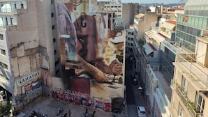 A street view with a large mural on a building, a narrow alley, parked motorcycles, and a white car. - Luxury Living Athens  (Athens)