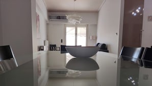 A modern kitchen with a central island, a hanging light fixture, and a window providing natural light. - Luxury Living Athens  (Athens)