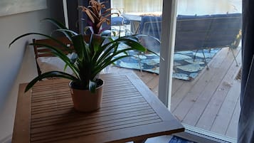 Une pièce avec une table en bois et une chaise, une plante en pot, et une vue sur un lac, visible à travers une porte vitrée.