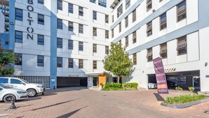 Un edificio moderno con la segnaletica "The Bolton", un'area di parcheggio e un ingresso curato con aiuole.