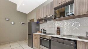Una cucina moderna con mobili in legno, elettrodomestici in acciaio inossidabile e un rivestimento a motivi decorativi.