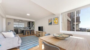 A modern living room with a sofa, dining table, and kitchen in the background.