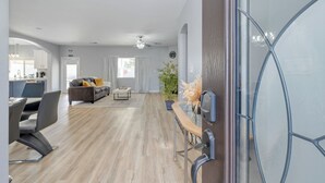 A modern living room with a wooden floor, a sofa, a coffee table, and a dining area with chairs. - Spacious 4-bedroom house with Pool, Fun BackYard & Amazing Game Room (Bakersfield)