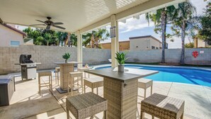 An outdoor patio with a pool, wicker furniture, a grill, and a ceiling fan. - Spacious 4-bedroom house with Pool, Fun BackYard & Amazing Game Room (Bakersfield)