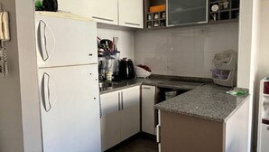 A modern kitchen with white cabinets, a granite countertop, and a built-in microwave. - Ambientes Baires (Buenos Aires)