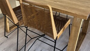 A wooden dining table with four woven chairs and a black metal frame. - Ambientes Baires (Buenos Aires)