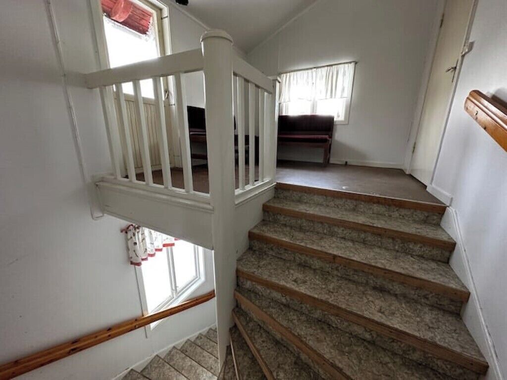 A staircase with wooden steps and white railings leading to a landing.