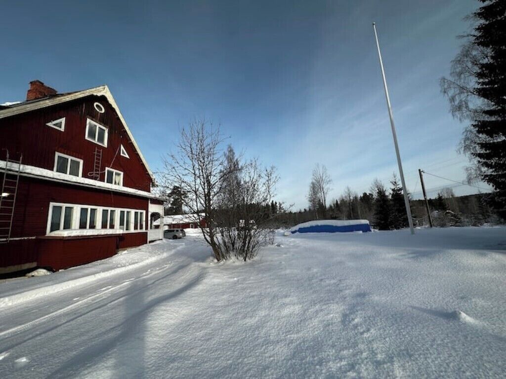 A snow-covered street with a red building on the left and a clear blue sky.