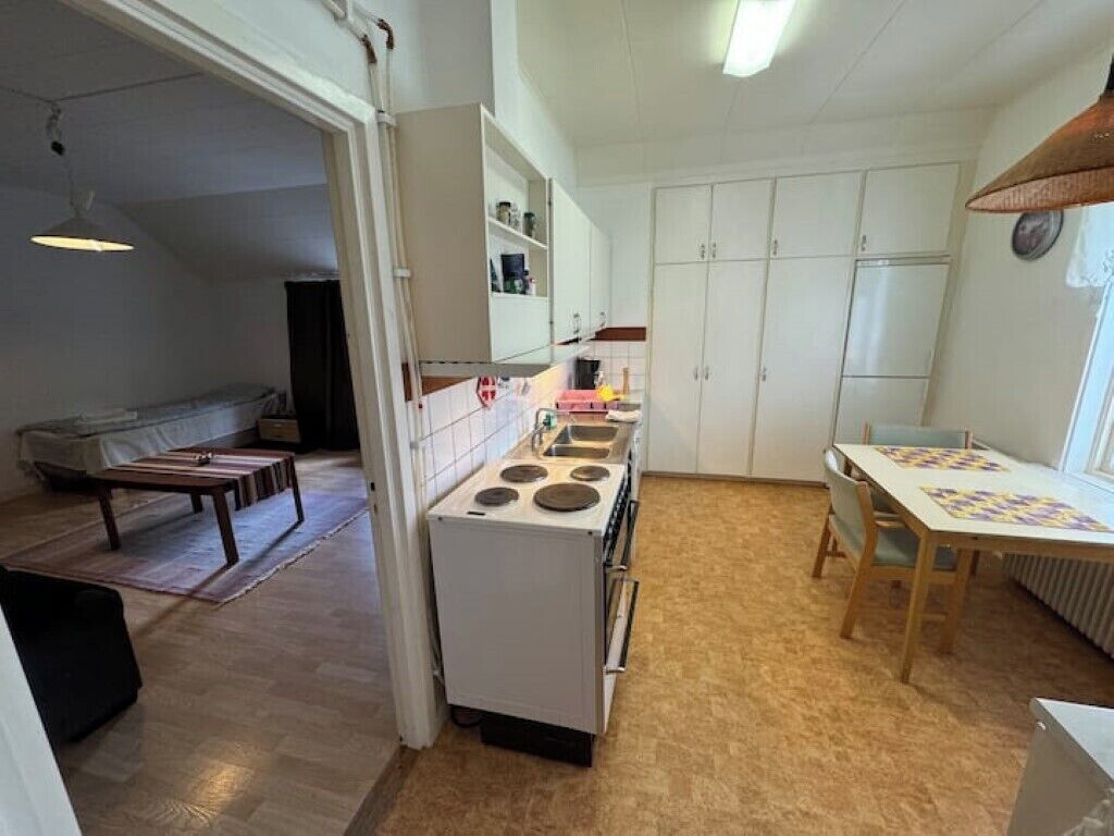 A compact kitchen with a stove, cabinets, and a dining area with a table and chairs.