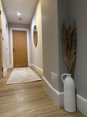 Stylish hallway with a door, rug, and decorative vase.
