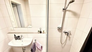 A bathroom with a sink, mirror, towel rack, and shower.