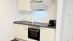 A compact kitchen with white cabinets, a built-in oven, and a sink.