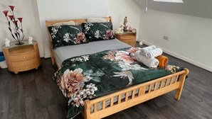 Une chambre à coucher avec un lit en bois, une lucarne, une table de chevet et une commode.