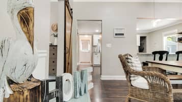 Un intérieur moderne avec un plancher en bois, une chaise en osier et un panneau indiquant « MAISON ».