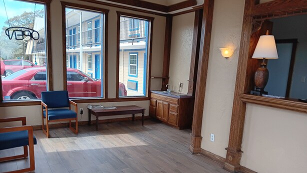 A spacious room with large windows, a wooden bench, a small table, and a kitchen area with wooden cabinets. - Ball Parks Inn (Branson)