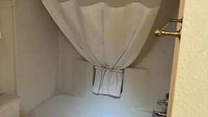 A bathroom with a bathtub, a shower curtain, and a door handle. - Ball Parks Inn (Branson)