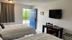 A hotel room with two beds, a TV, a desk, and a window with curtains. - Ball Parks Inn (Branson)