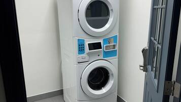A compact, modern laundry room with a front-loading washer and dryer, a control panel, and a door with a window.