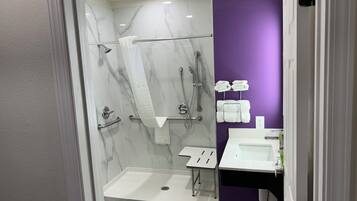 Een moderne badkamer met een inloopdouche, handgrepen, een witte wastafel en een paarse accentmuur.