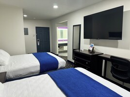 Quarto de hotel com duas camas, uma escrivaninha, uma TV e um espelho.
