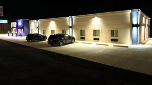 Ein Gebäude mit Parkplatz und zwei geparkten Autos davor.