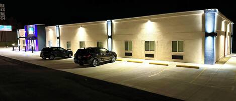 A building with a parking lot and two cars parked in front.