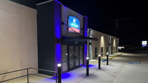 Außenansicht eines Hotels bei Nacht, mit beleuchteter Beschilderung für 'LakeSide Inn & Suites' und 'Physio & Wellness'.