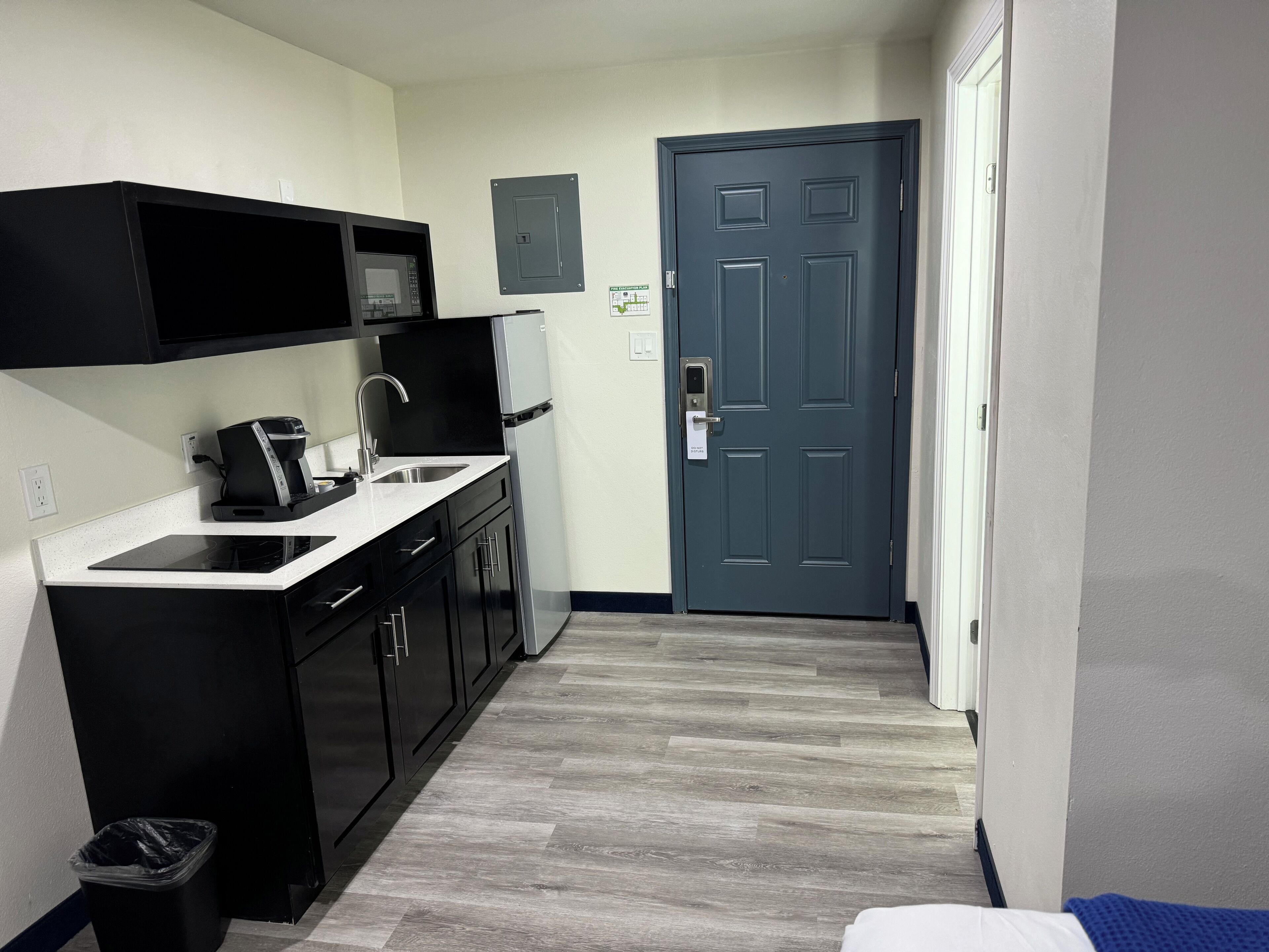 A compact kitchen with black cabinets, a stainless steel sink, and a coffee maker.