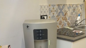 Un distributeur d’eau dans un coin cuisine, avec un mur recouvert de carreaux et un évier.
