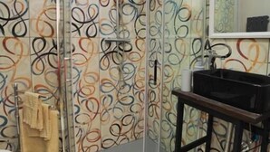 Une salle de bain avec une douche à parois de verre, un lavabo et un miroir.