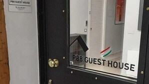 Une porte noire avec un miroir qui reflète un couloir et une autre porte portant l’inscription « P88, MAISON D’HÔTES ».