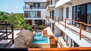 A modern building with a swimming pool, wooden deck, and multiple balconies. - LaFamilia Casa and Suites (Isla Holbox)