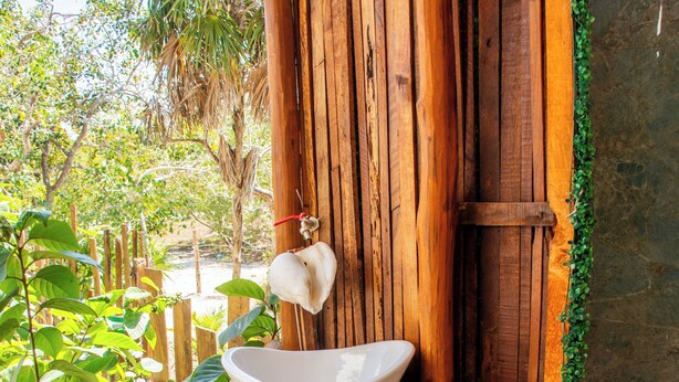 A rustic wooden structure with a white basin and a wooden stool. - LaFamilia Casa and Suites (Isla Holbox)
