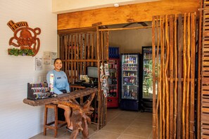Un interior rústico con mostrador de madera, televisor y refrigerador lleno de bebidas.
