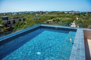 Una piscina azul cristalina con vistas a la costa y edificios al fondo.
