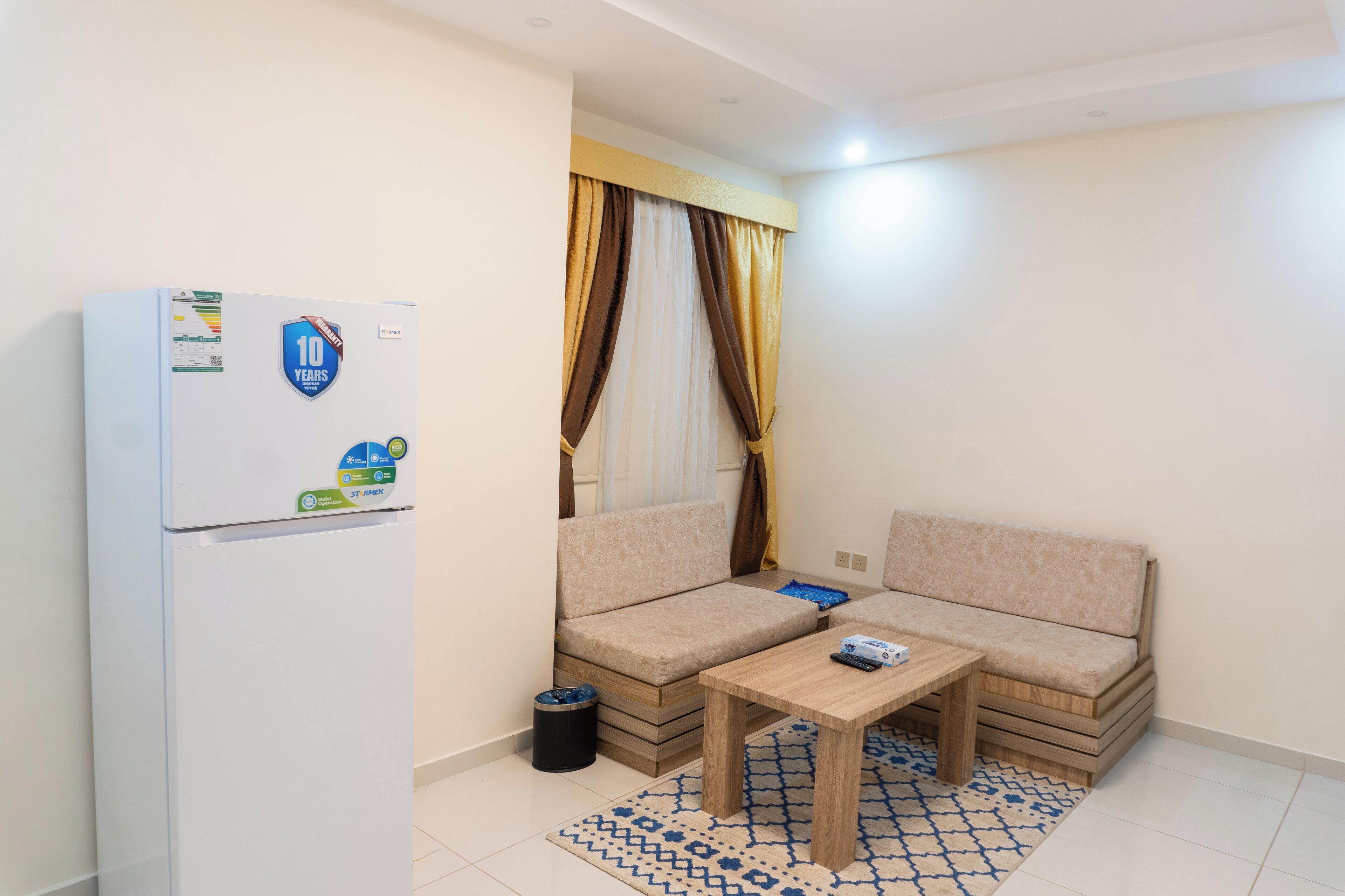 Un espacio habitable compacto con sofá, una mesita y un refrigerador.
