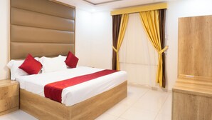 Un dormitorio moderno con una cama de madera, ropa de cama roja y blanca, cabecera, mesita de noche y armario.