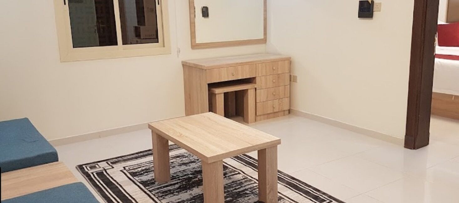 A small room with a wooden table, a blue sofa, a cabinet, and a window.