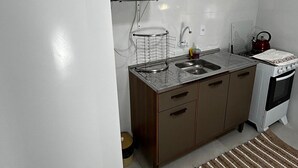 Μια μικρή, λειτουργική κουζίνα με ένα λευκό ψυγείο, έναν φούρνο μικροκυμάτων, έναν νεροχύτη και μια κουζίνα.
