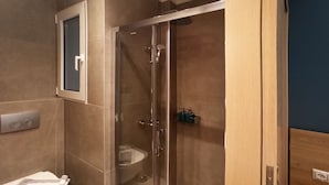 Et moderne badeværelse med brusekabine i glas, toilet og håndvask.