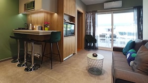 Et moderne køkken med spiseplads, et rundt sofabord og en sofa med farverige puder.