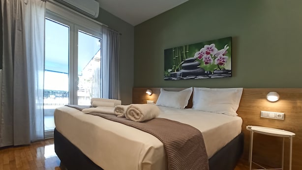 Et hotelværelse med en stor seng, havudsigt, et orkidémaleri og et lille natbord.
