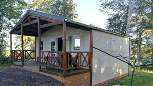Een klein, gelijkvloers vakantiehuis met een houten terras en een overdekte veranda.