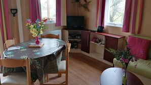 Een gezellige kamer met een eettafel, stoelen, een televisie en een bank.