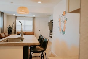 Una cocina moderna con comedor, una isla grande y una obra de arte colgada en la pared.