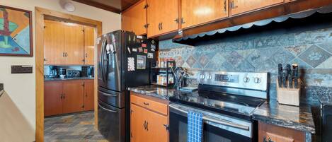 A kitchen with wooden cabinets, a stainless steel refrigerator, a stove, and a tiled backsplash.