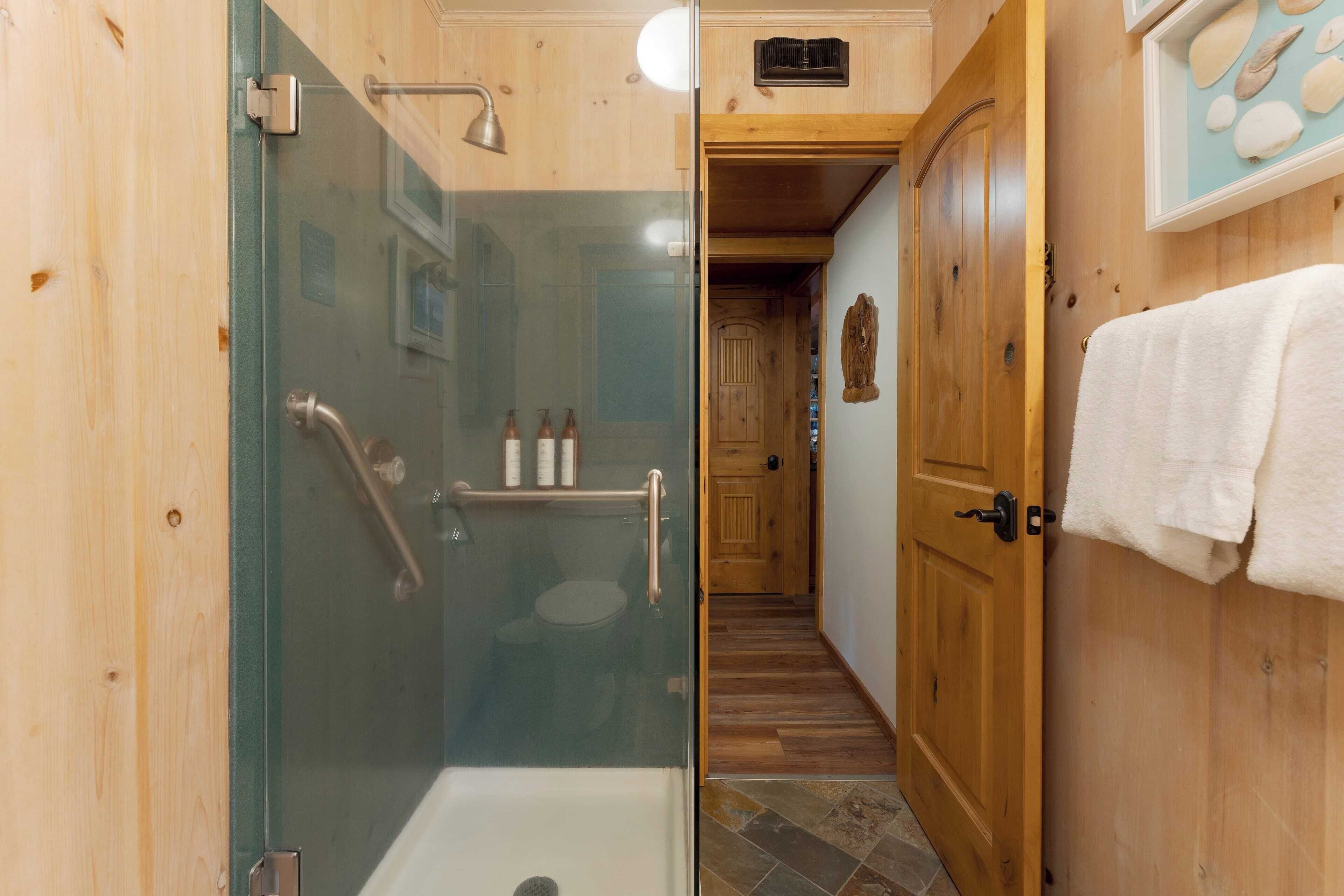 A wooden interior with a glass-enclosed shower, a wooden door, and a towel rack.