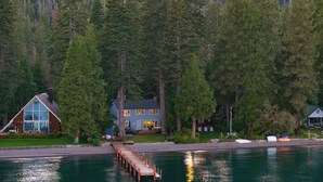 A lakeside cabin with a dock extending into the water, surrounded by dense forest. - Lakefront Haven by Avantstay Minutes to Ski Resorts Private Dock (Homewood)